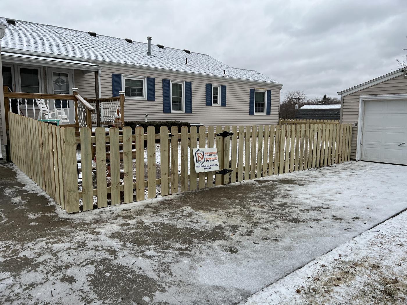 Spaced picket fence and gate in snow with the Drennen-Searcy yard sign